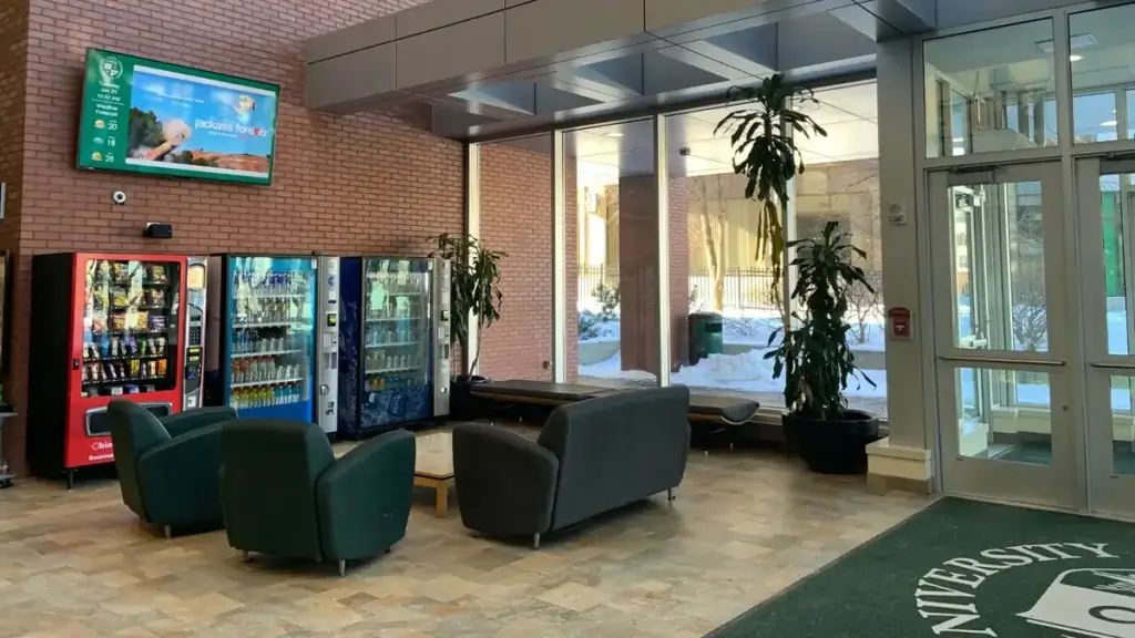 Reach Media Network Colleges Higher Ed digital signage University lounge digital signage by Reach Media Network featured above snack and drink machines.