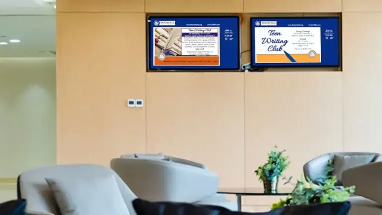 Digital signage screens from Reach Media Network featured in main lobby, displaying announcements and local weather.
