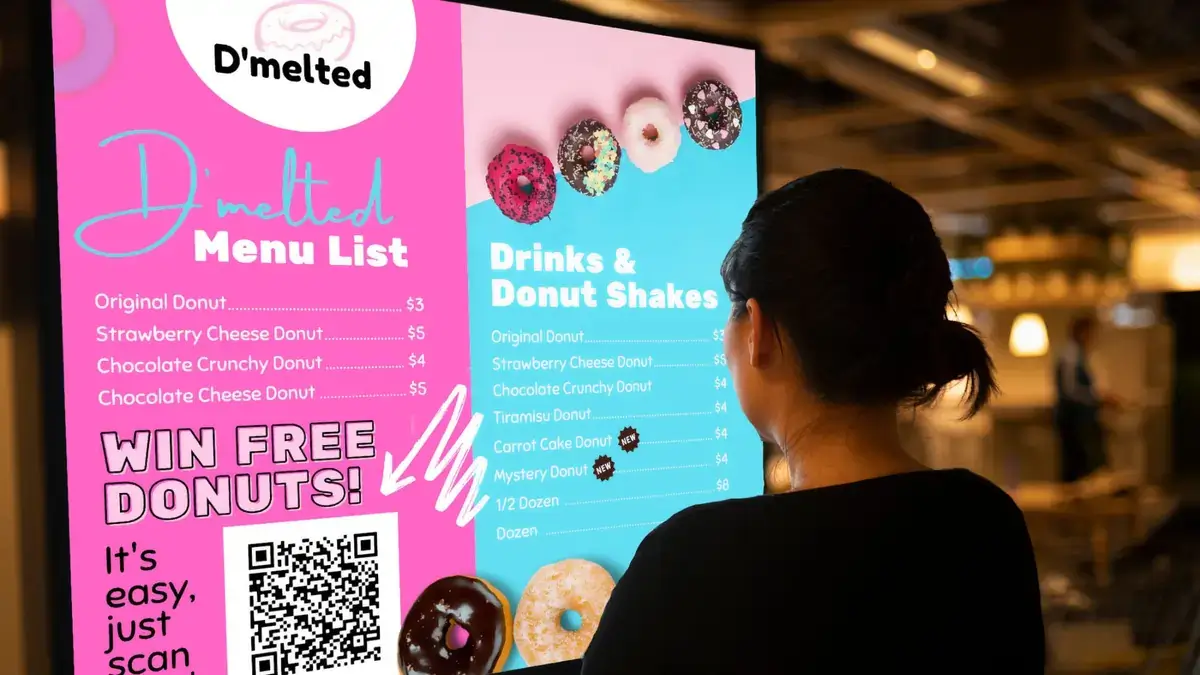 Reach-Media-Network-menu-board-digital-signage-D'melted Customer looking at the D'melted digital signage menu board from Reach Media Network